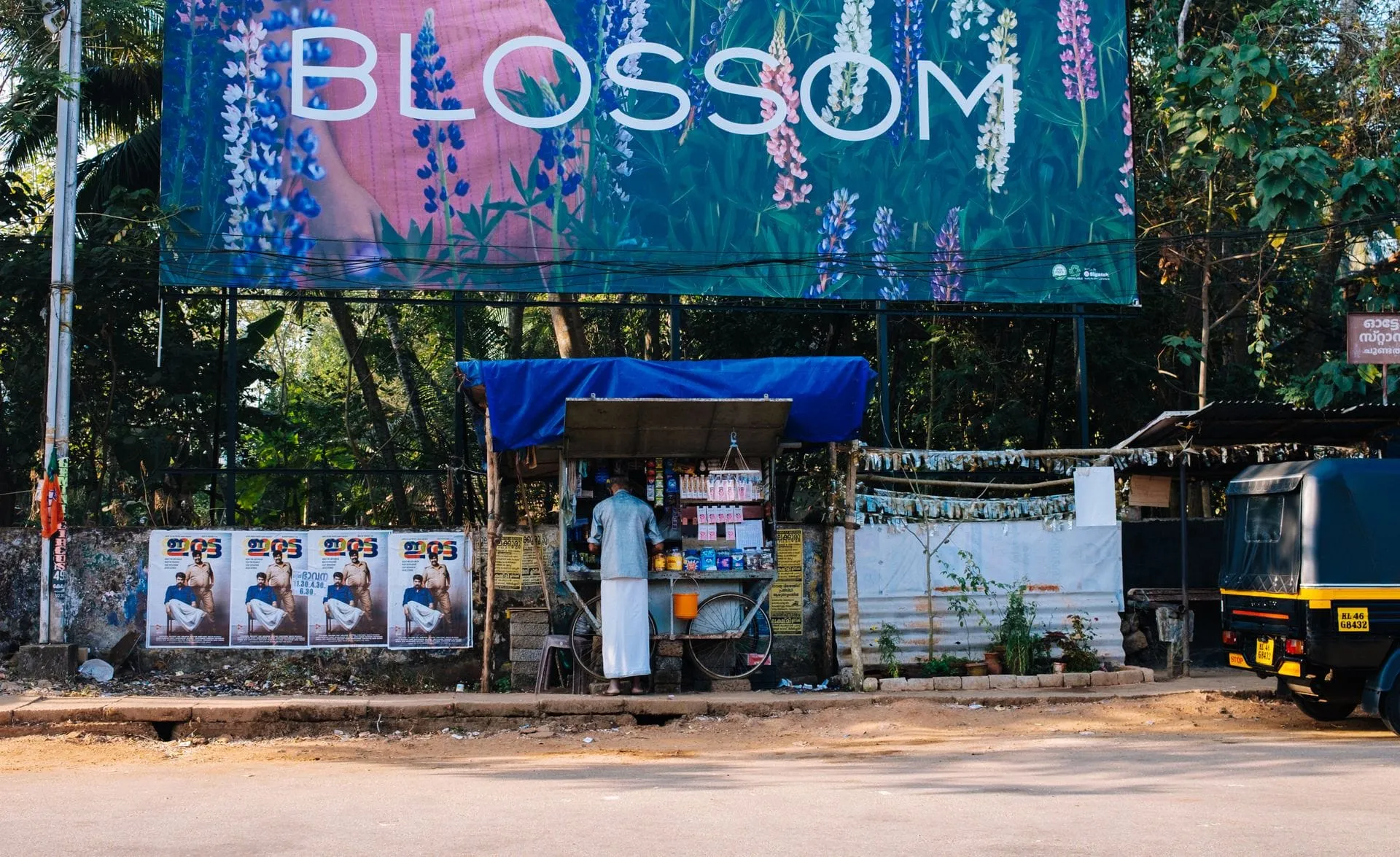 Large roadside hoarding above a small street stall in Kochi, India